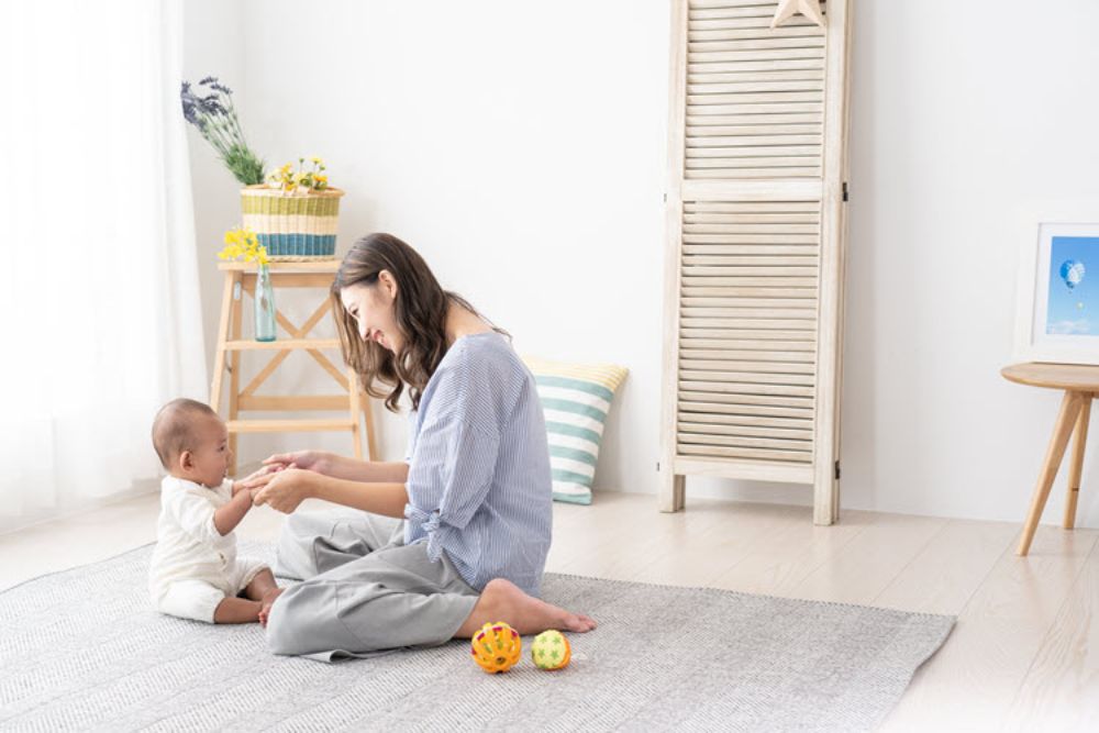 Bé 1 tuổi đang lăn bóng qua lại với ba mẹ, tạo không khí vui vẻ