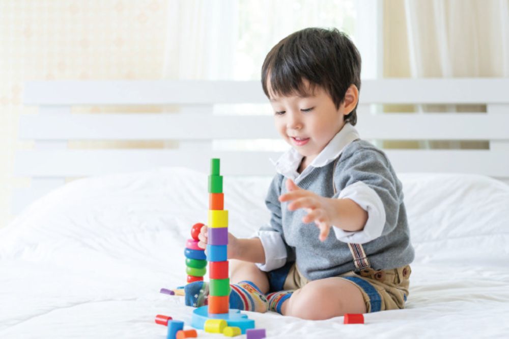 Bé 1 tuổi đang tập trung thả các hình khối nhiều màu sắc